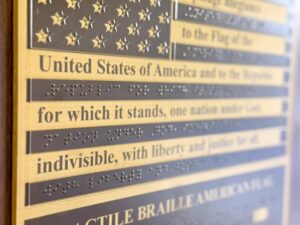 Close-up of the tactile Braille American Flag showing raised stars and Braille text from the Pledge of Allegiance that can be read by touch.