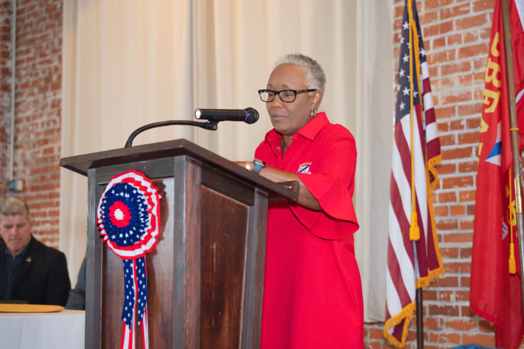 Mayor Anita R. Levy stands at a podium delivering remarks during her swearing-in ceremony on July 1, 2026. American and municipal flags are displayed behind her as she addresses attendees during the inauguration of the City of Abbeville's new administration.